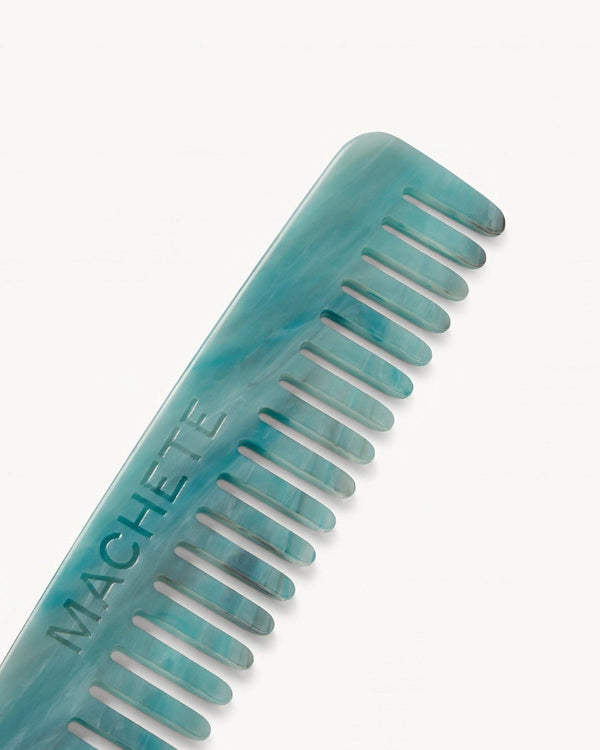 Turquoise comb with 'Machete' branding on a white background