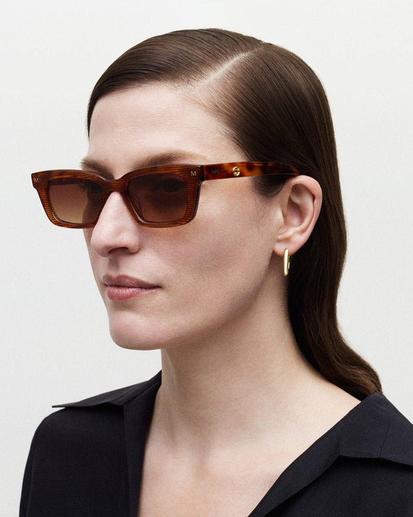 Woman wearing brown sunglasses from INDY New York with a neutral background