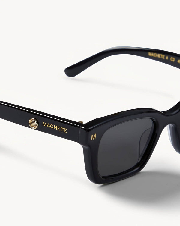 Black sunglasses with gold accents on a white background
